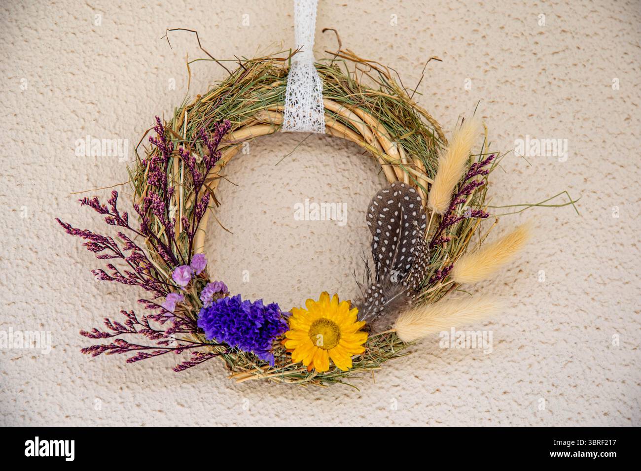 La corona fatta a mano presenta un assortimento di fiori secchi, tra cui girasoli, lavanda e piume. Foto Stock