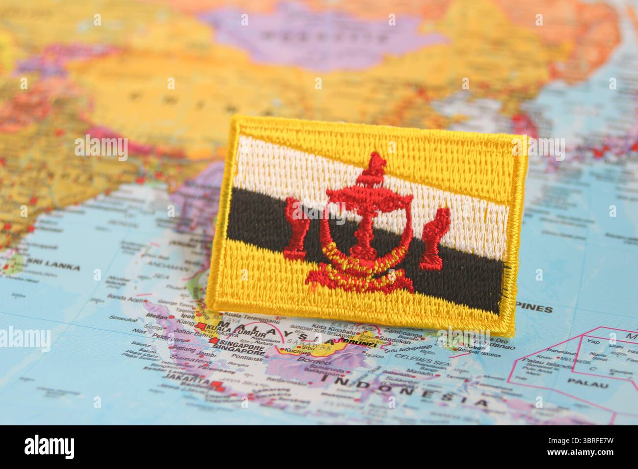 Bandiera del Brunei ecologica realizzata in tessuto e filo, posizionata su una mappa del mondo presso la sede del Brunei, che rappresenta il patriottismo e la sostenibilità. Foto Stock