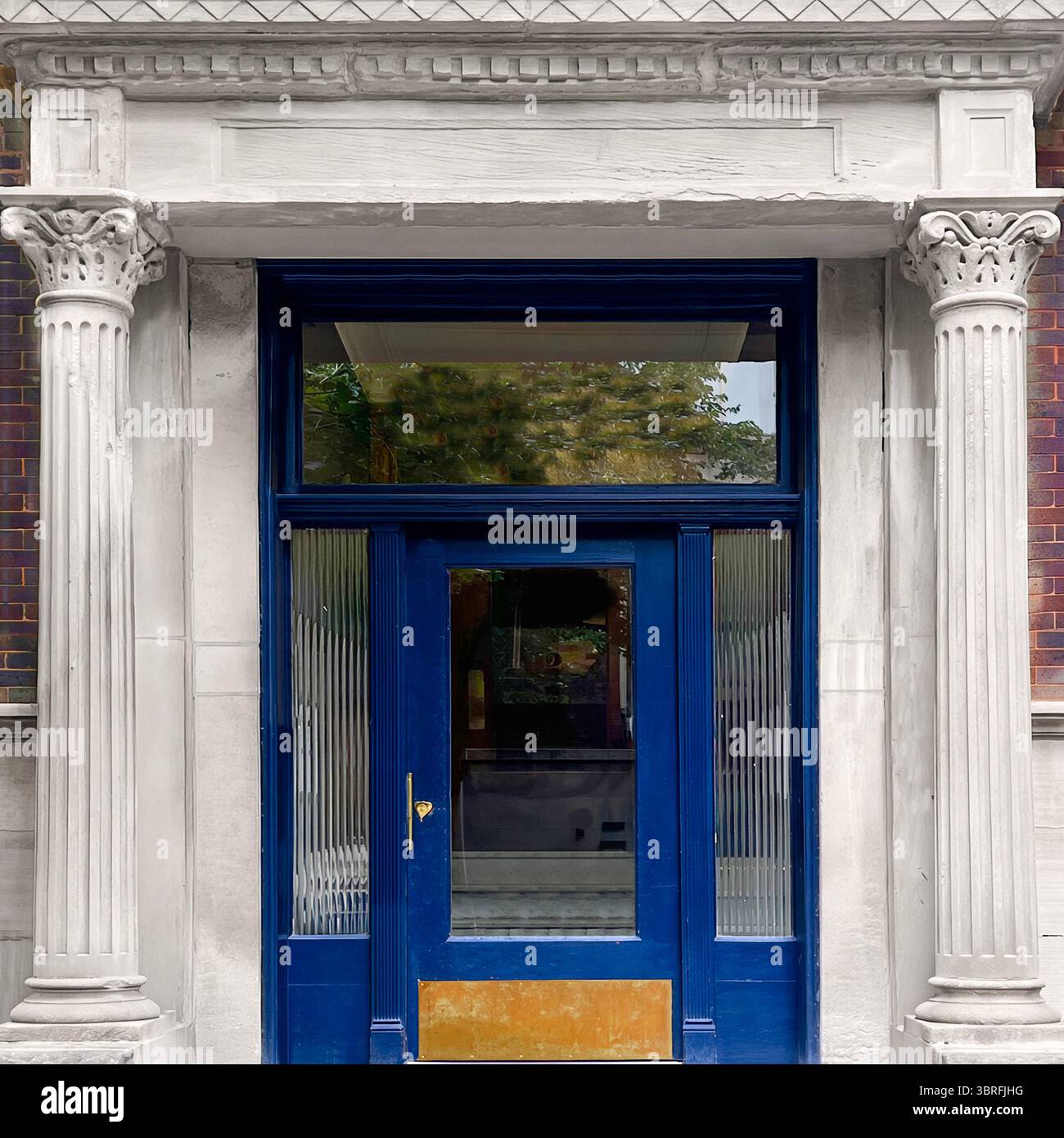 Porta blu navy con accenti dorati incastonata tra colonne in pietra classica e capitelli ornati, un ingresso neoclassico in un edificio residenziale di Chicago. Foto Stock