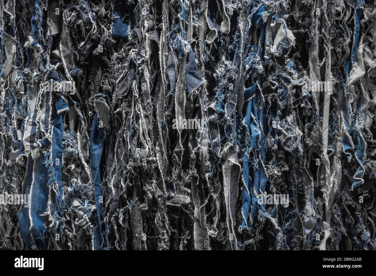 Vista dettagliata che mette in evidenza la complessa trama del denim strappato riutilizzato come jeans riciclati, mostrando moda ecocompatibile e tessuti sostenibili Foto Stock