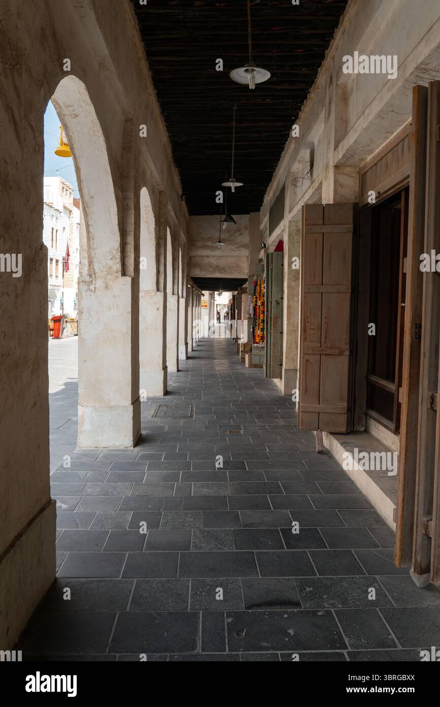 Mercato tradizionale del Qatar con negozi e negozi, completamente vuoto e senza persone. Architettura storica mediorientale e tranquillo bancomat urbano Foto Stock