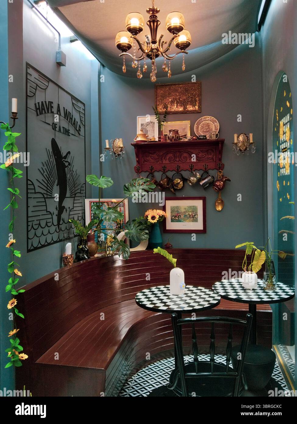 Maesai, Chiangrai, Tailandia - 2024 maggio: Uno spazio caffe' ben decorato con un'atmosfera vintage, caratterizzato da un murale, piante e lampadari classici Foto Stock