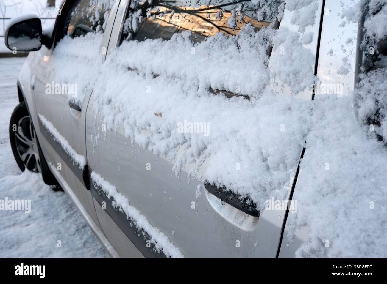 Uno spesso strato di neve copre un'auto color argento parcheggiata all'esterno. Foto Stock