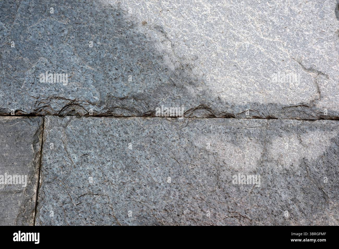 Linee e trame intricate si formano sulla superficie della pavimentazione in pietra grigia. Foto Stock