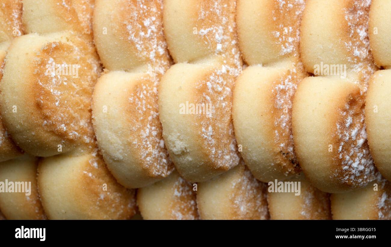 Gli involtini dolci appena sfornati sono disposti in primo piano, mostrando le loro morbide croste dorate. Gli strati delicati sono leggermente spolverati con lo zucchero, invi Foto Stock