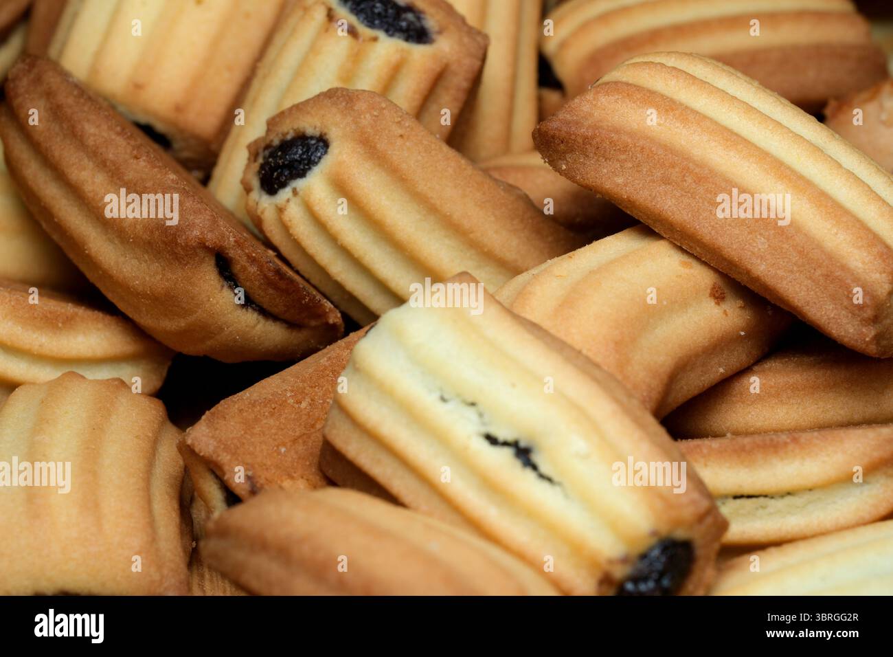 Un'allettante disposizione di biscotti a strati appena sfornati, con sfumature dorate-marroni e ripieni dolci che sbirciano. Questo delizioso invi Foto Stock