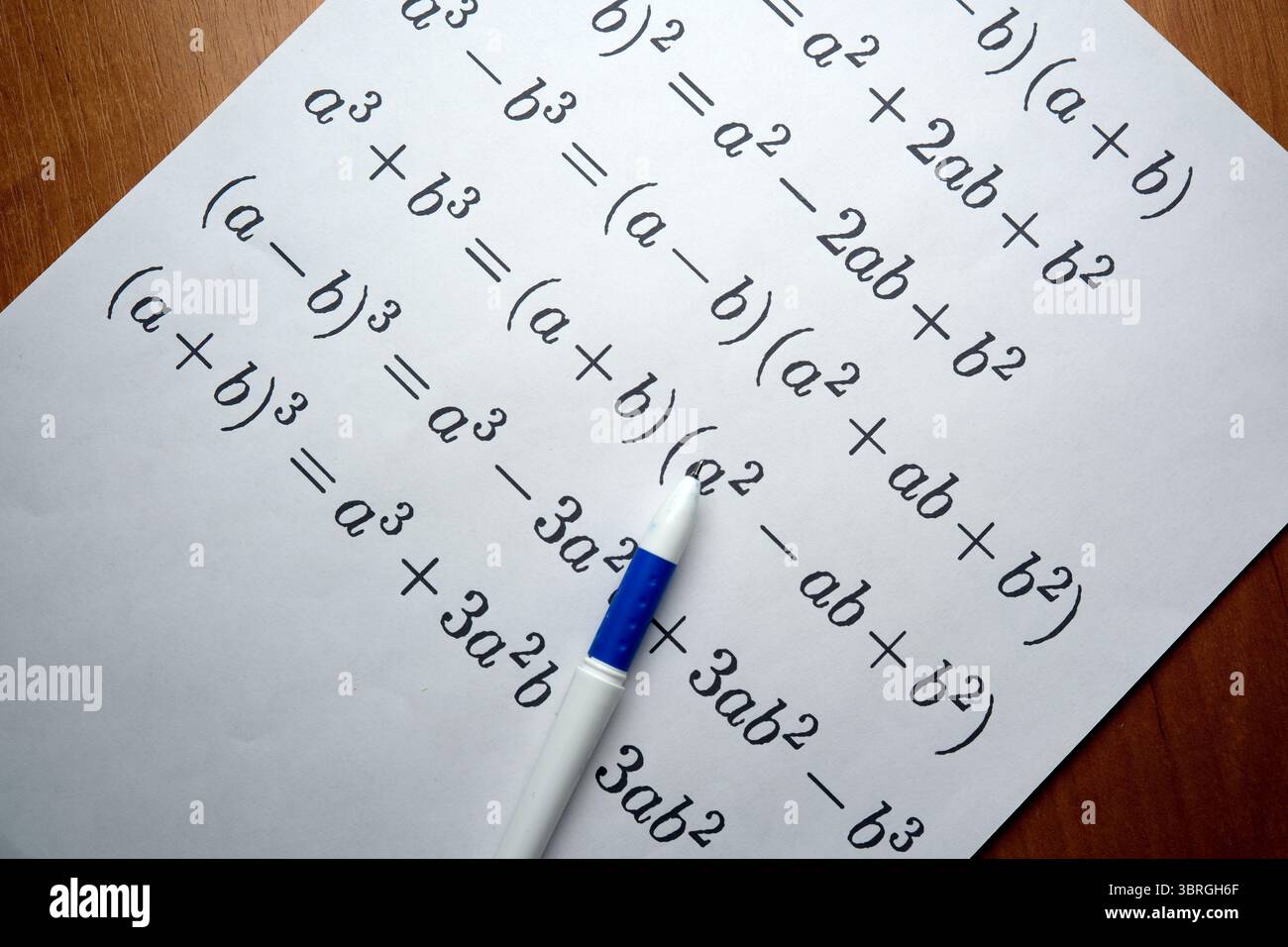 Identità algebriche scritte a mano visualizzate su un nitido white paper. Foto Stock
