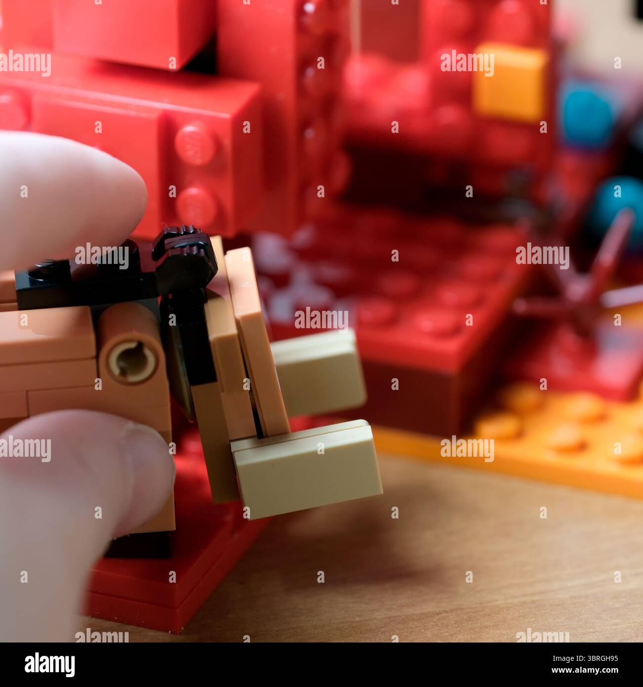 Le mani assemblano abilmente blocchi vivaci in un design fantasioso. Foto Stock