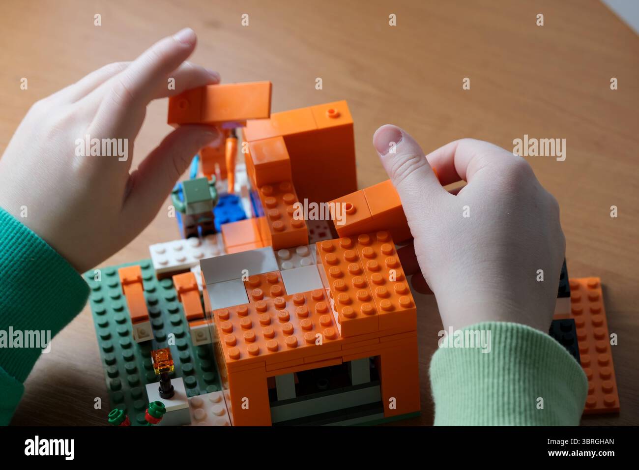 Le mani assemblano abilmente blocchi colorati in una zona di costruzione giocosa. Foto Stock