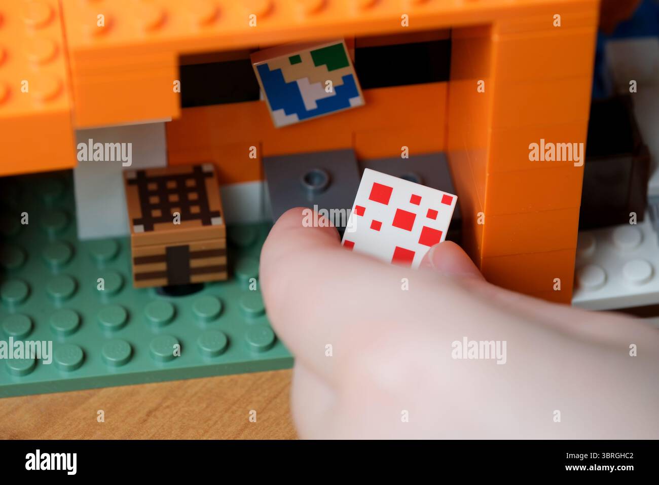 Una mano interagisce con una struttura vibrante fatta di blocchi da costruzione. Foto Stock