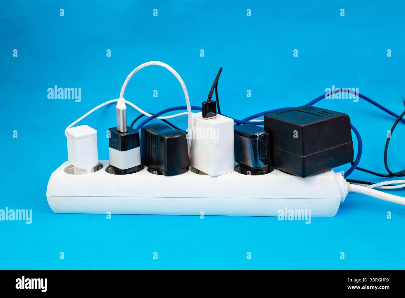 Molti caricabatterie per smartphone o tablet sono collegati a una grande presa di prolunga di colore blu Foto Stock