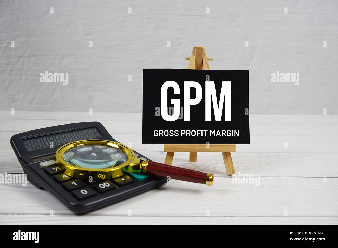 GPM abbreviazione del testo del margine di profitto lordo con lente d'ingrandimento e calcolatrice su sfondo in legno Foto Stock