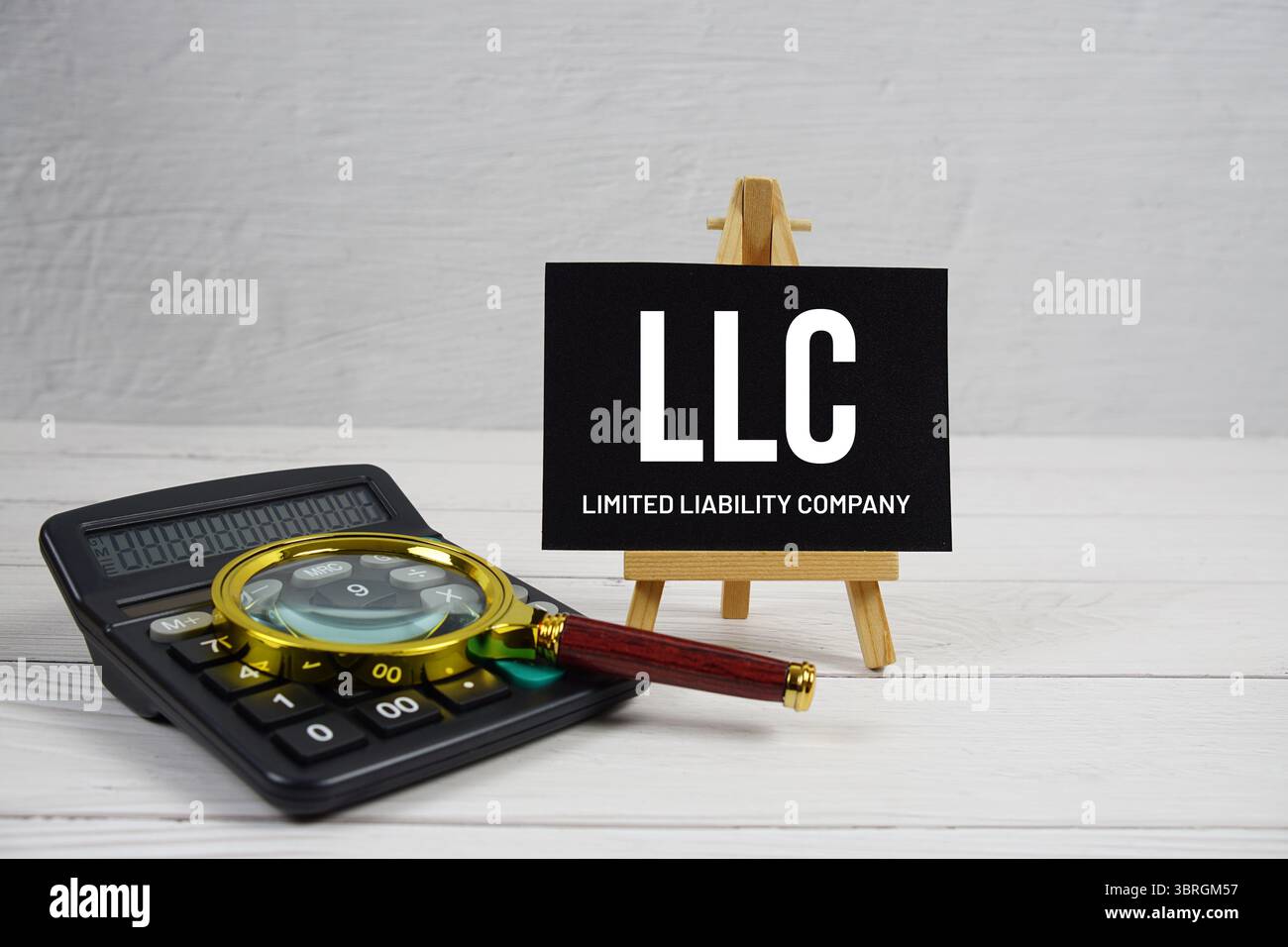 LLC abbreviazione di Limited Liability Company testo con lente d'ingrandimento e calcolatrice su sfondo in legno Foto Stock