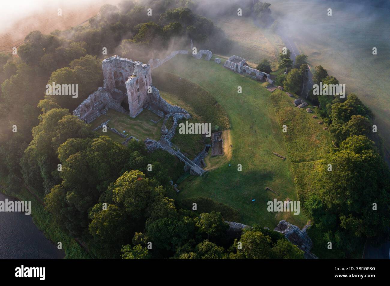 Castello di Norham uno dei più importanti castelli di confine nella nebbia estiva sul fiume Tweed Foto Stock