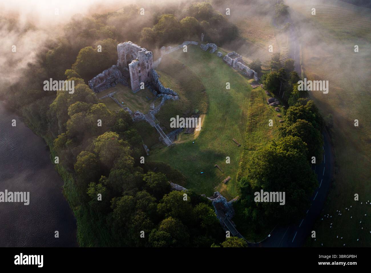 Castello di Norham uno dei più importanti castelli di confine nella nebbia estiva sul fiume Tweed Foto Stock