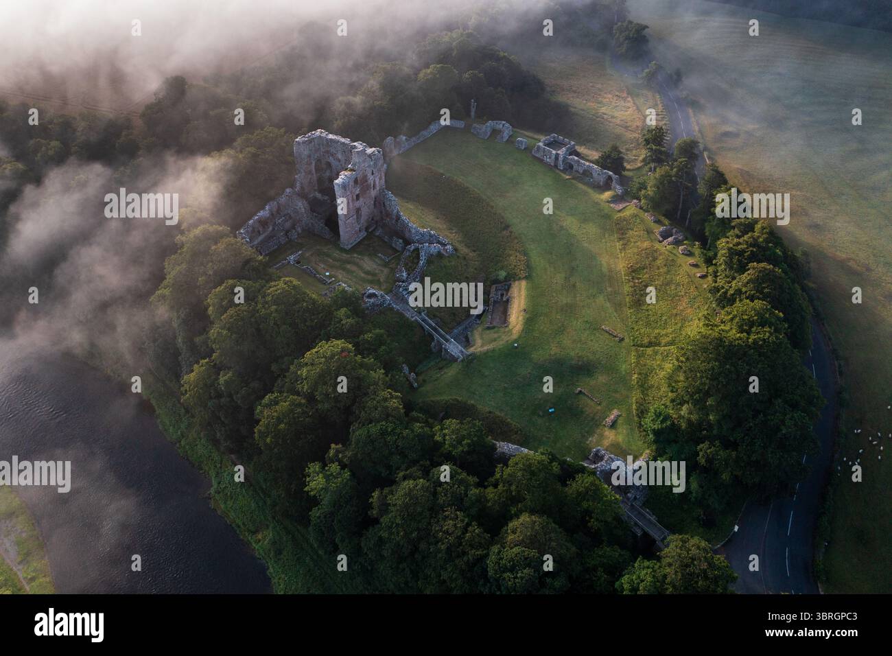 Castello di Norham uno dei più importanti castelli di confine nella nebbia estiva sul fiume Tweed Foto Stock