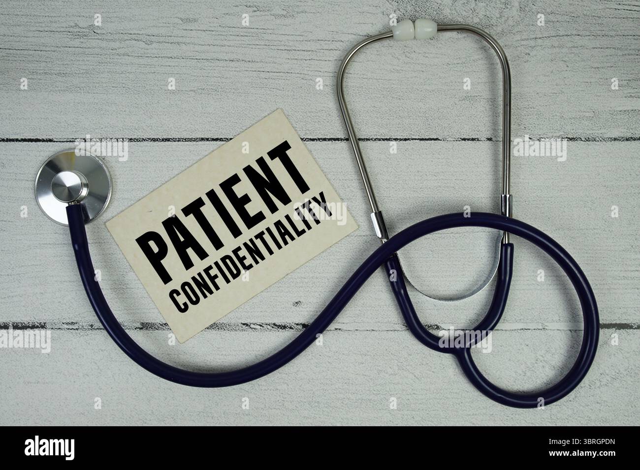 Testo sulla riservatezza del paziente con stetoscopio medico su sfondo in legno Foto Stock