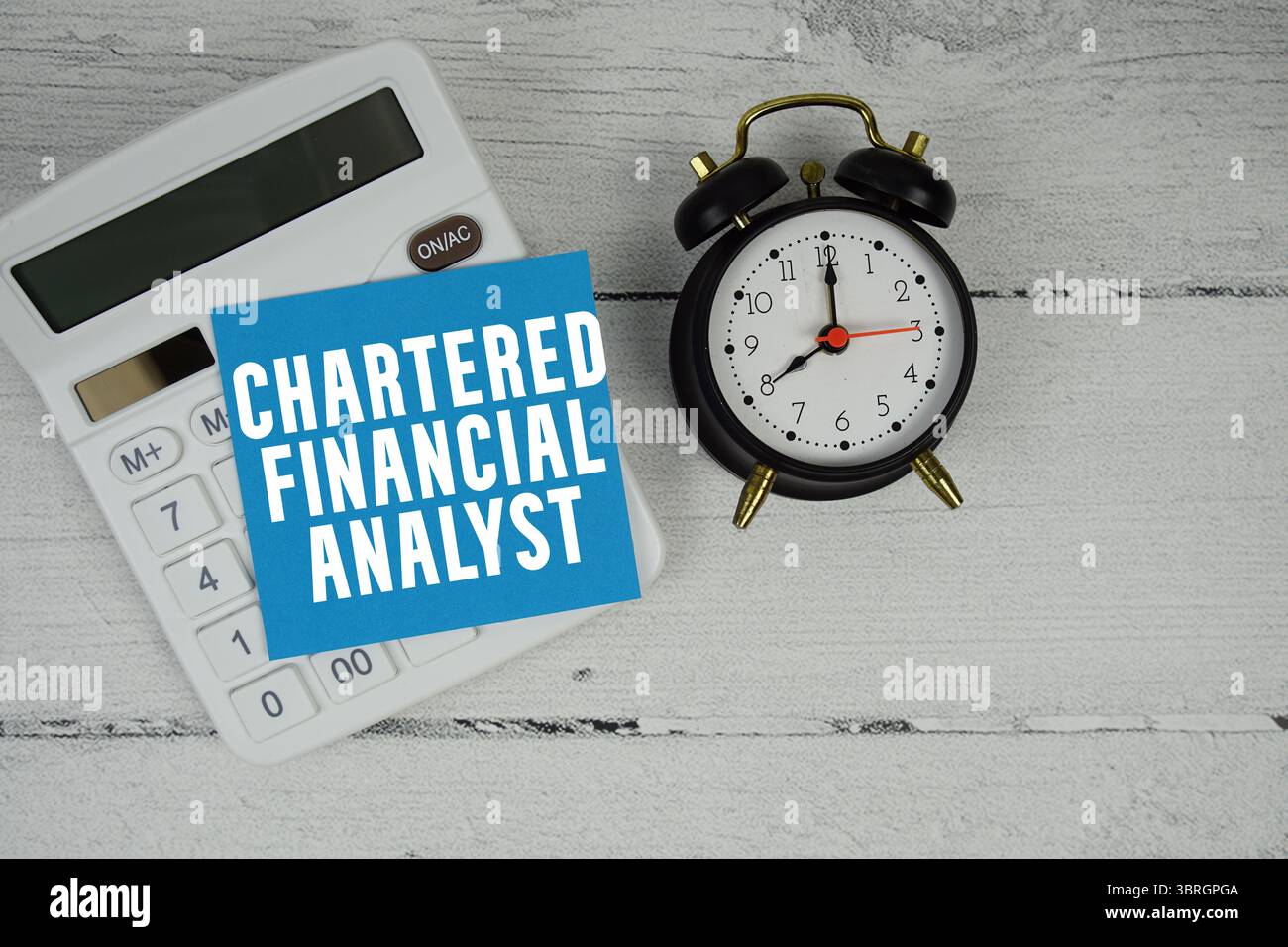Testo Chartered Financial Analyst con calcolatrice e sveglia su sfondo in legno Foto Stock