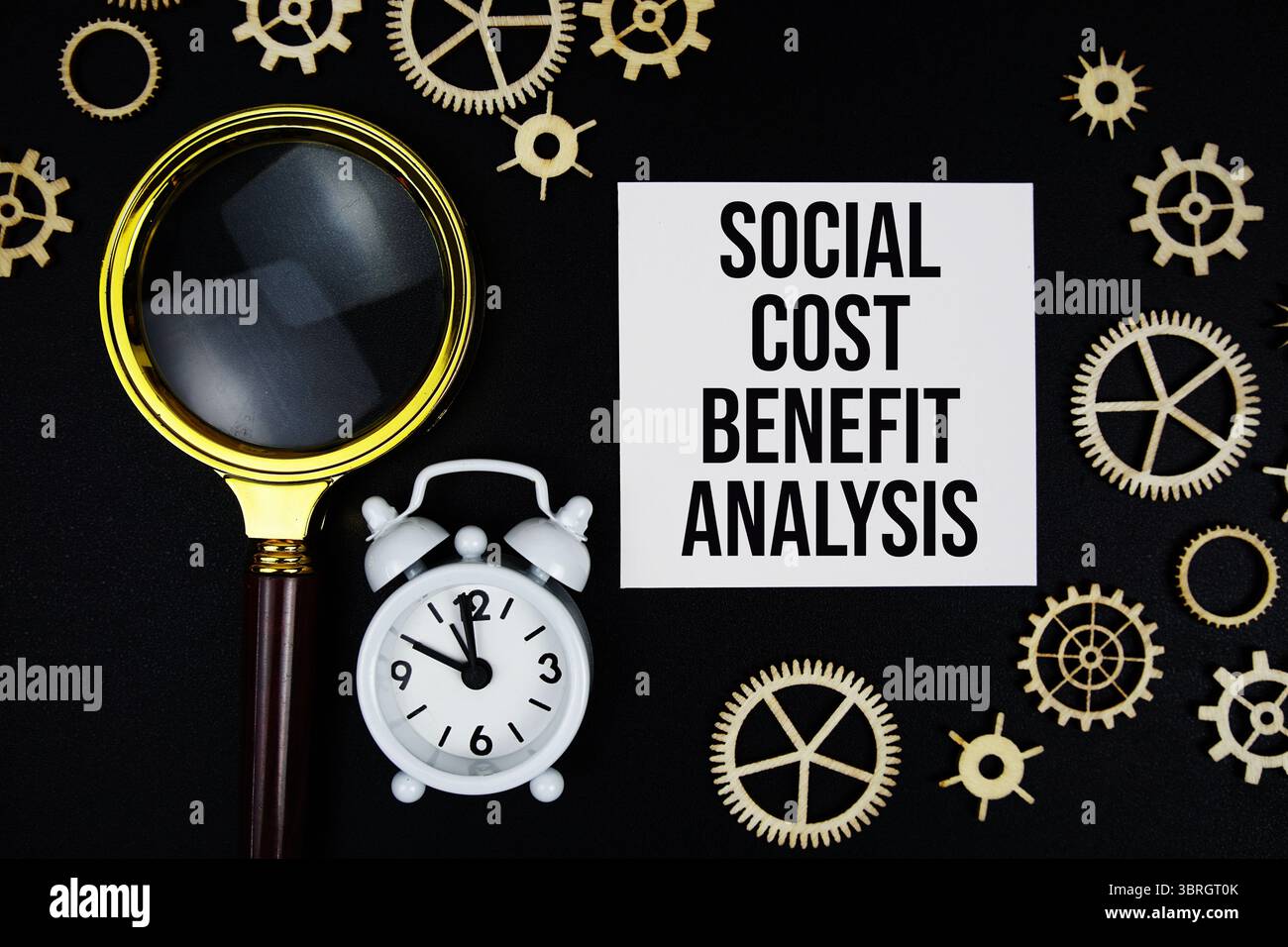 SCBA - messaggio di testo Social Cost Benefit Analysis su una nota adesiva con lente d'ingrandimento e sveglia su sfondo nero Foto Stock