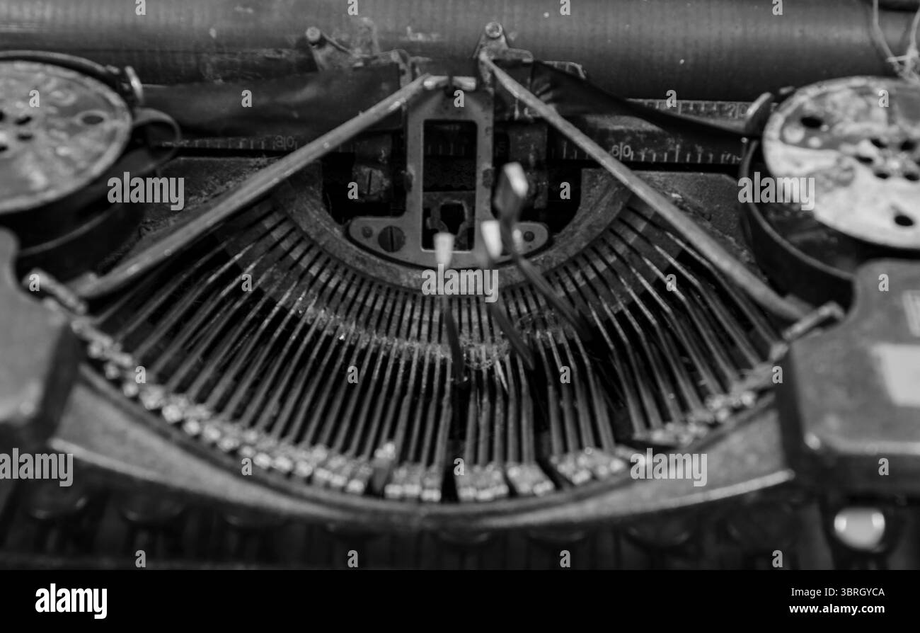 Immagine in primo piano monocromatica del carattere di sulla vecchia macchina da scrivere rotta con alcune lettere attaccate in posizione sollevata Foto Stock