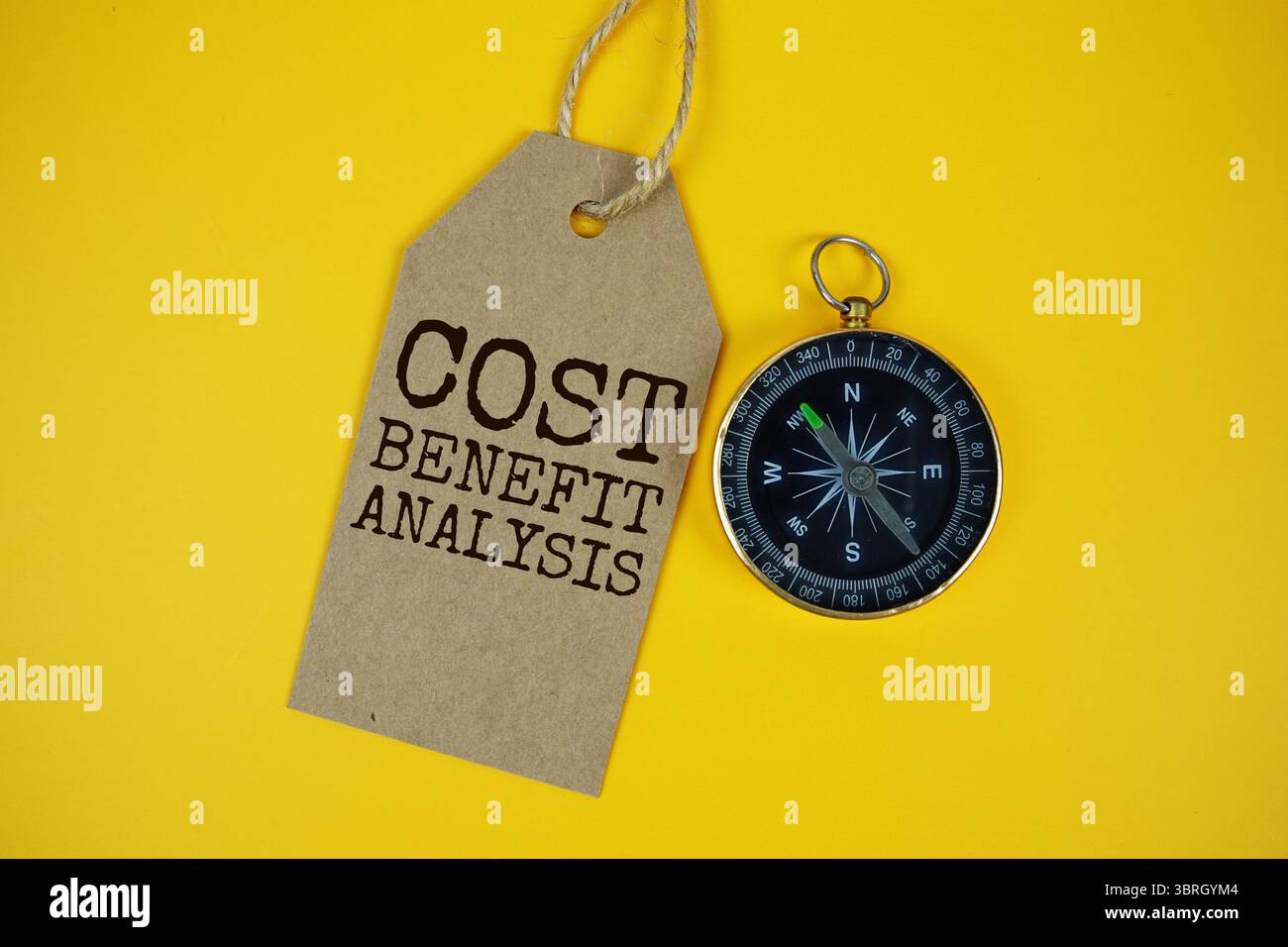 Testo dell'analisi dei costi e benefici sul cartellino dei prezzi con bussola sullo sfondo del cartone in sughero Foto Stock