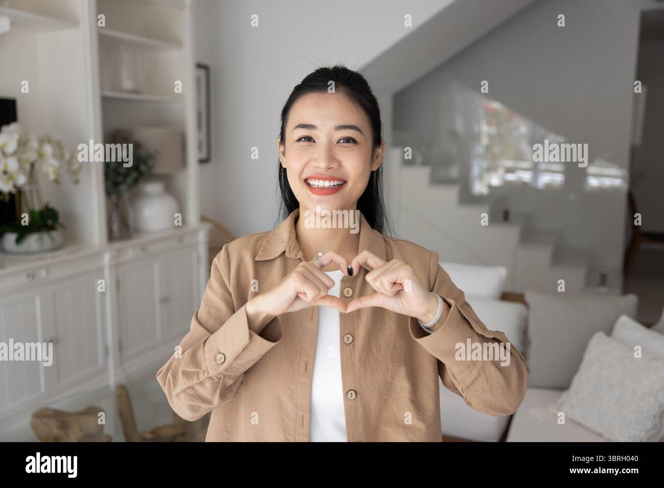 Donna che mostra simbolo di amore e affetto con le dita unite Foto Stock