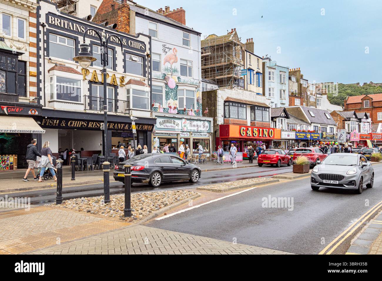 Vivace strada sul lungomare a Scarborough, North Yorkshire, con negozi, caffetterie e turisti vicino a South Bay Beach, una popolare destinazione turistica del Regno Unito. Foto Stock