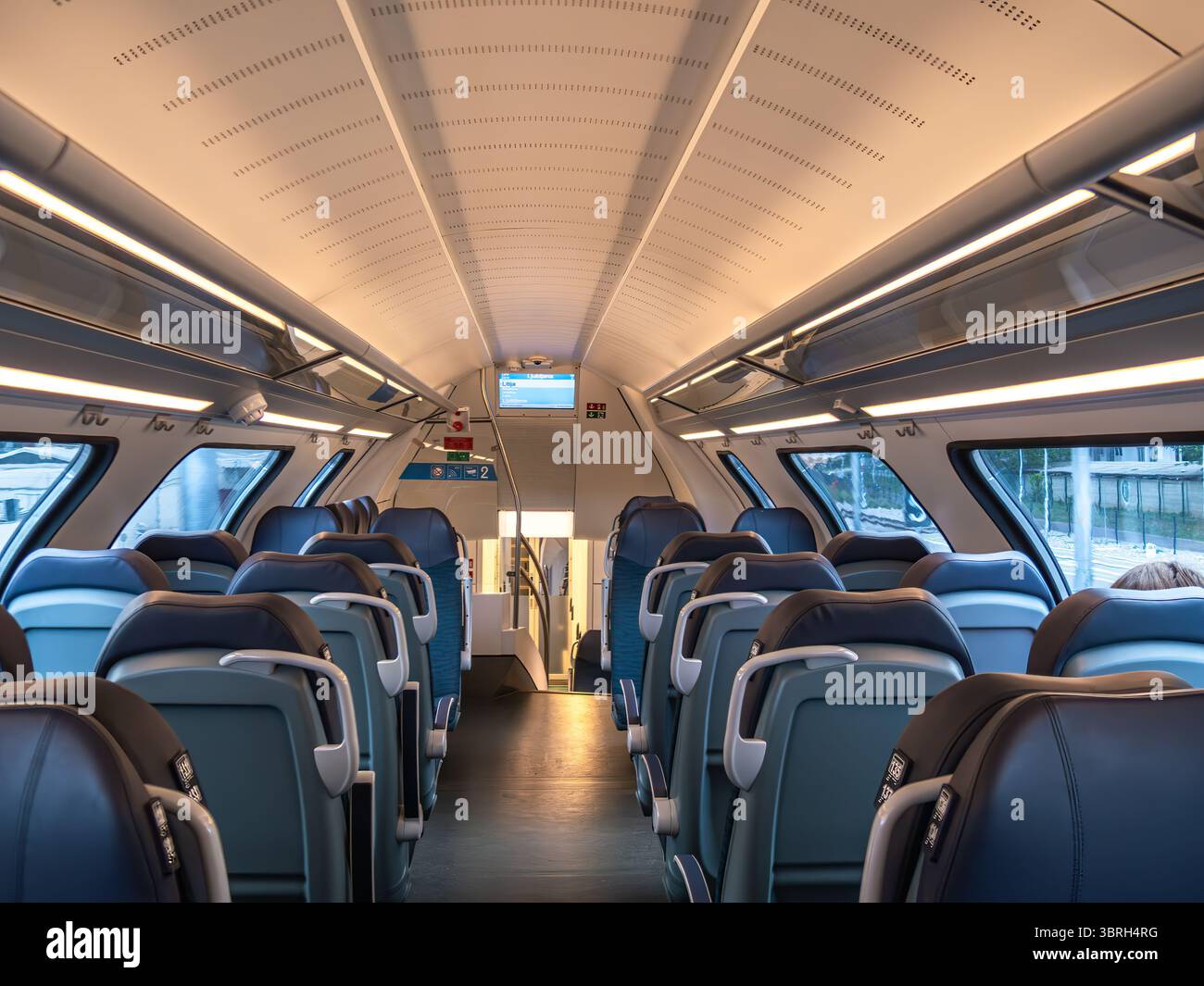 Interni di un treno moderno con posti vuoti e illuminazione dall'alto. Foto Stock