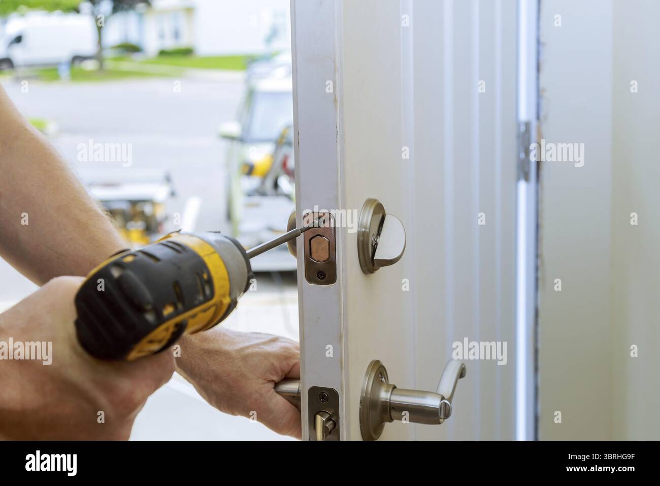 Uomo che ripara il pomello della porta. Chiusura delle mani del lavoratore che installa il nuovo armadietto della porta Foto Stock