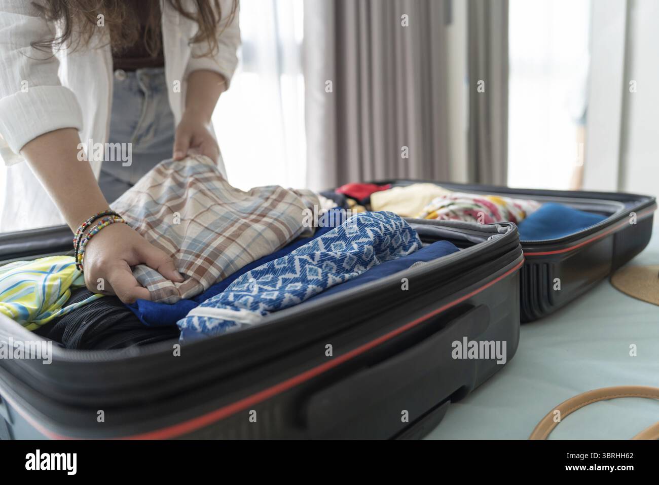 Donna che trasporta la valigia sul letto per una nuova lista di viaggio per pianificare il viaggio preparando la vacanza Prenota ora viaggio trasporto Foto Stock