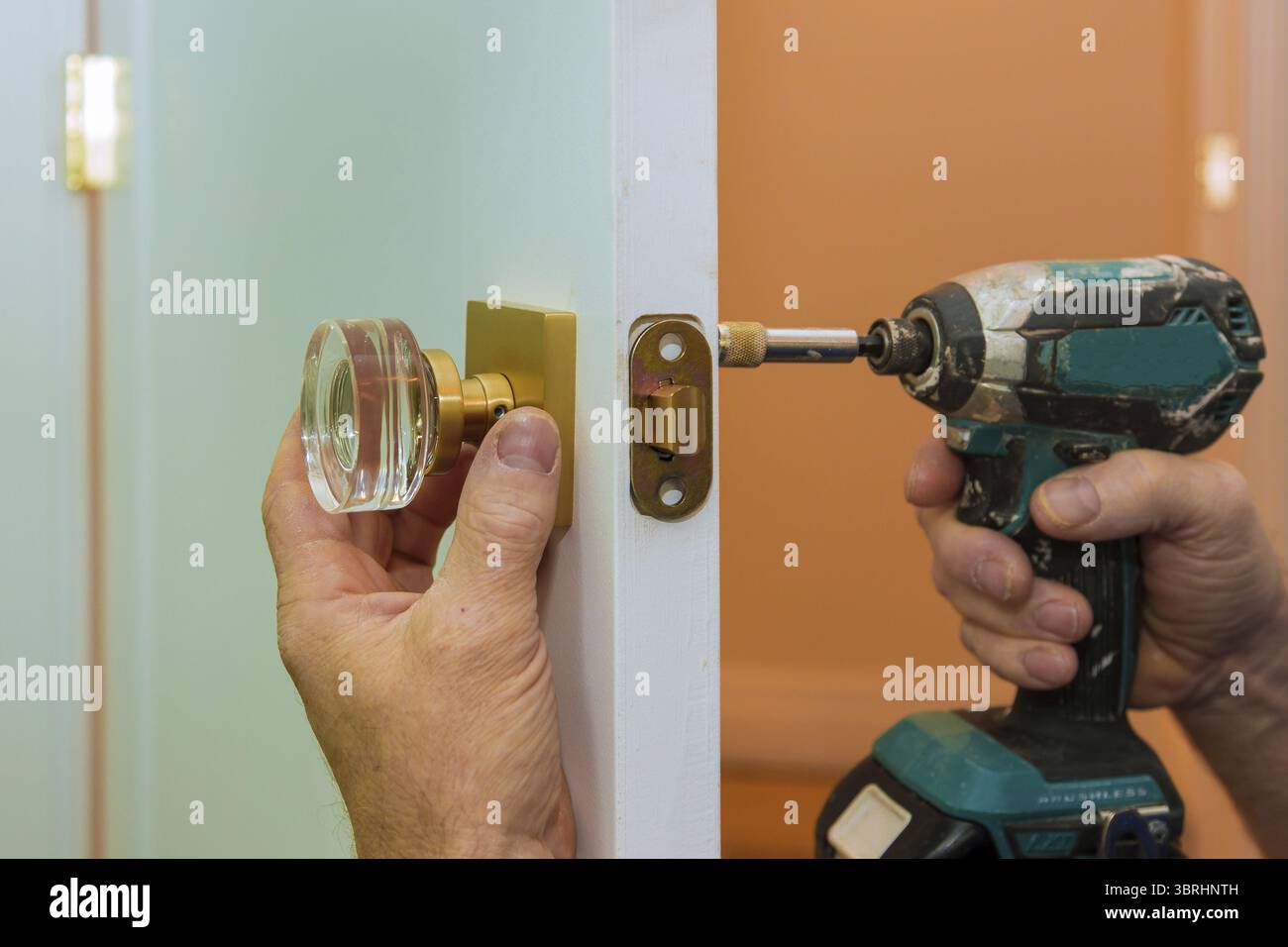 Uomo che ripara la chiocoseup della manopola della porta delle mani di lavoro che installa nuovo armadietto della porta Foto Stock