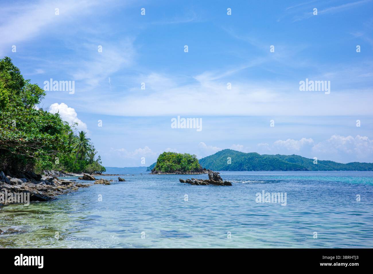 Una vista panoramica costiera di Palawan, Filippine, che mostra una tranquilla insenatura rocciosa con acque limpide e poco profonde che lambiscono dolcemente contro la splendida costa incontaminata Foto Stock
