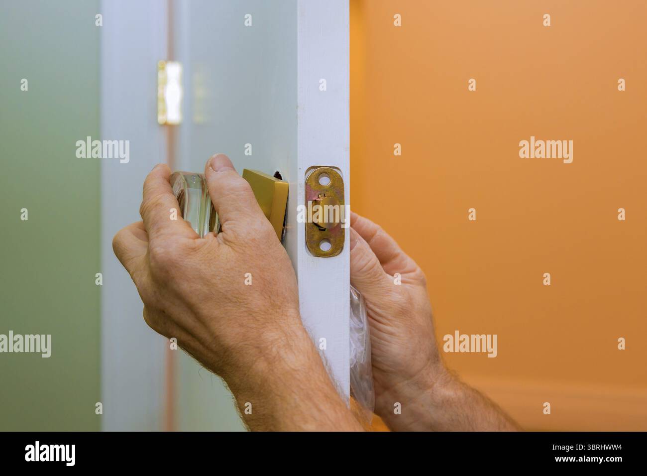 L'operatore ripara la serratura della portiera nelle mani del lavoratore installando una nuova armadietto della porta Foto Stock