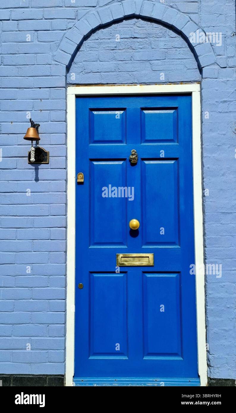 Porta d'ingresso in legno blu di una vecchia casa a dover con un'immagine di nave in metallo e una campanella vintage in ottone montata a parete, Kent, Regno Unito Foto Stock