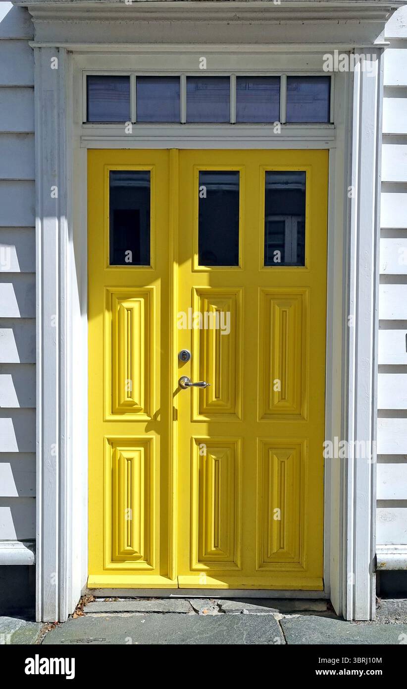 Porta d'ingresso gialla in legno in una casa bianca in lavagna nel vecchio quartiere storico di Gamle Stavanger, Norvegia Foto Stock