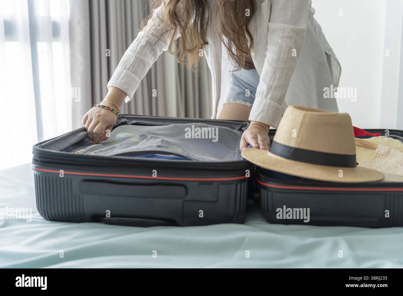 Donna che trasporta la valigia sul letto per una nuova lista di viaggio per pianificare il viaggio preparando la vacanza Prenota ora viaggio trasporto Foto Stock
