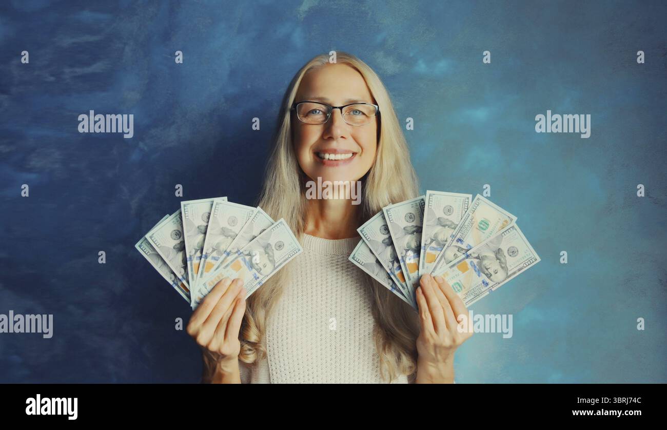 Ritratto di una donna di mezza età felice sorridente che tiene in mano soldi in contanti in banconote da un dollaro Foto Stock