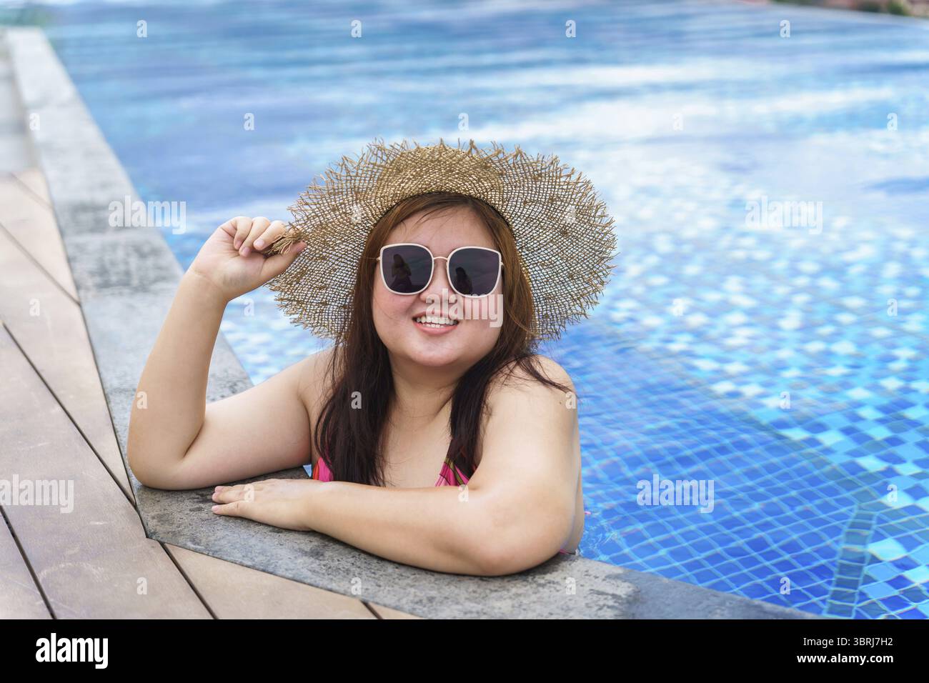 Giovane donna asiatica in sovrappeso che indossa costume da bagno arancione e cappello da spiaggia in paglia che si rilassa in piscina donna felice e di taglia allegra vacanza divertente in viaggio Foto Stock Giovane donna asiatica in sovrappeso che indossa costume da bagno arancione e cappello da spiaggia in paglia che si rilassa in piscina donna felice e di taglia allegra vacanza divertente in viaggio Foto Stock
