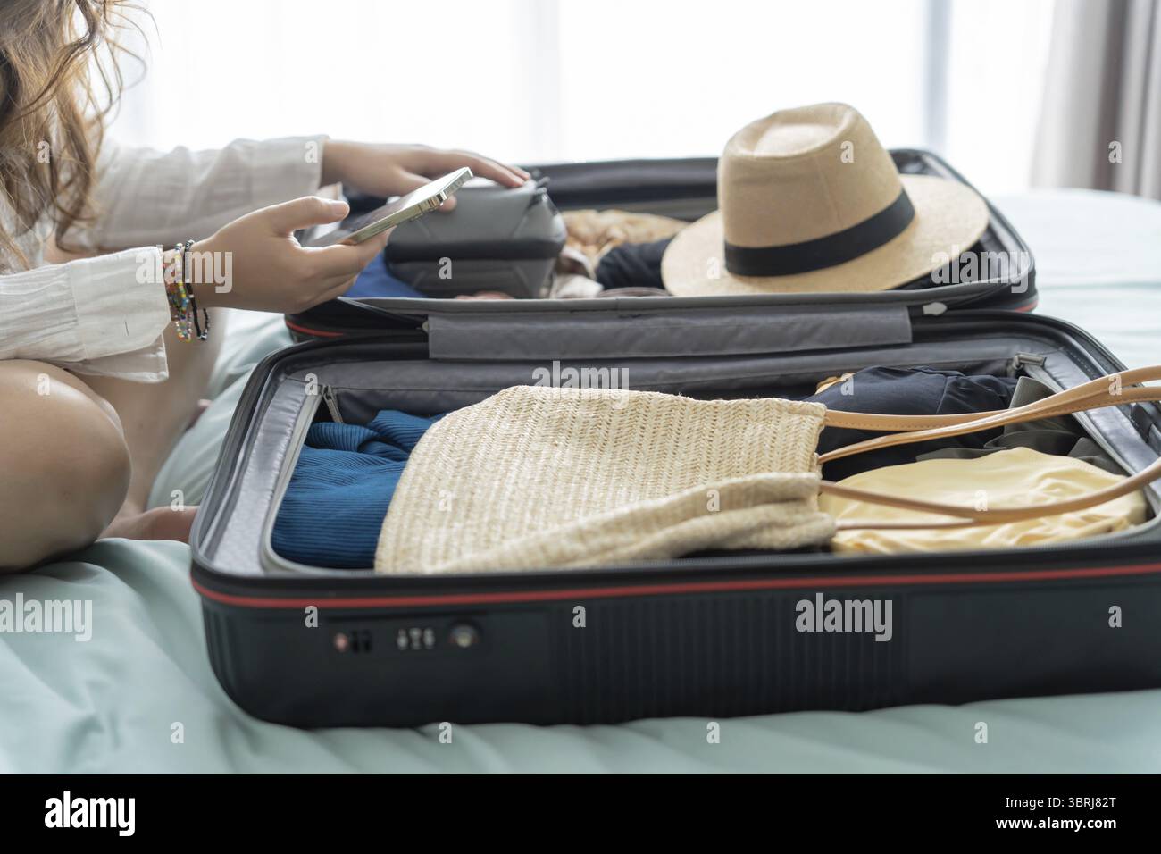 Donna che trasporta la valigia sul letto per una nuova lista di viaggio per pianificare il viaggio preparando la vacanza Prenota ora viaggio trasporto Foto Stock