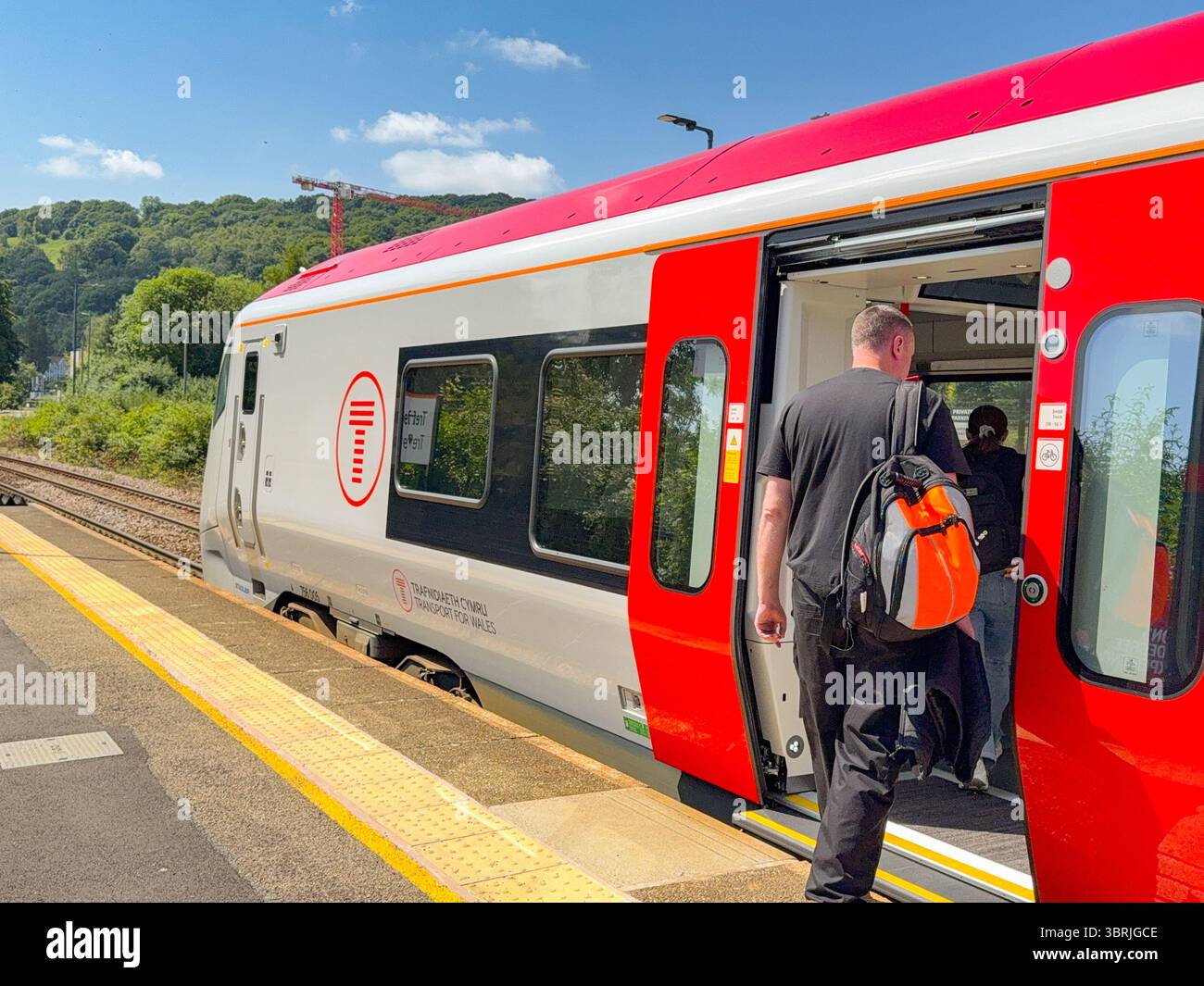 Treforest, Pontypridd, Galles, Regno Unito - 18 giugno 2025: Persona che prende un treno pendolare Transport for Wales Classe 756 alla stazione di Treforest. Foto Stock