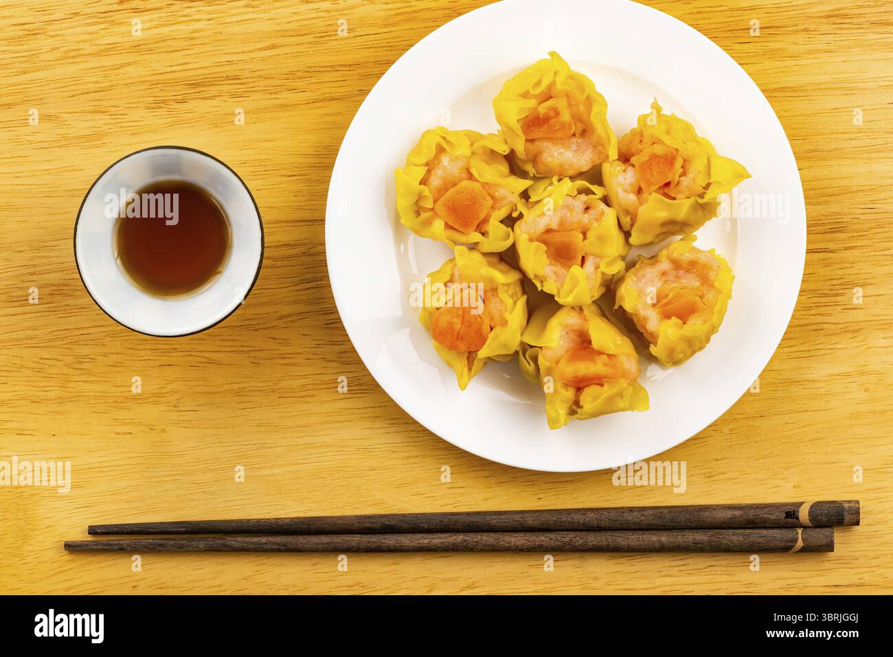 Vista dall'alto, piatto, delizioso gamberi fatti in casa, maiale tritato e tuorlo d'uovo salato gnocchi al vapore in un piatto di ceramica bianca con salsa in cerami bianchi Foto Stock