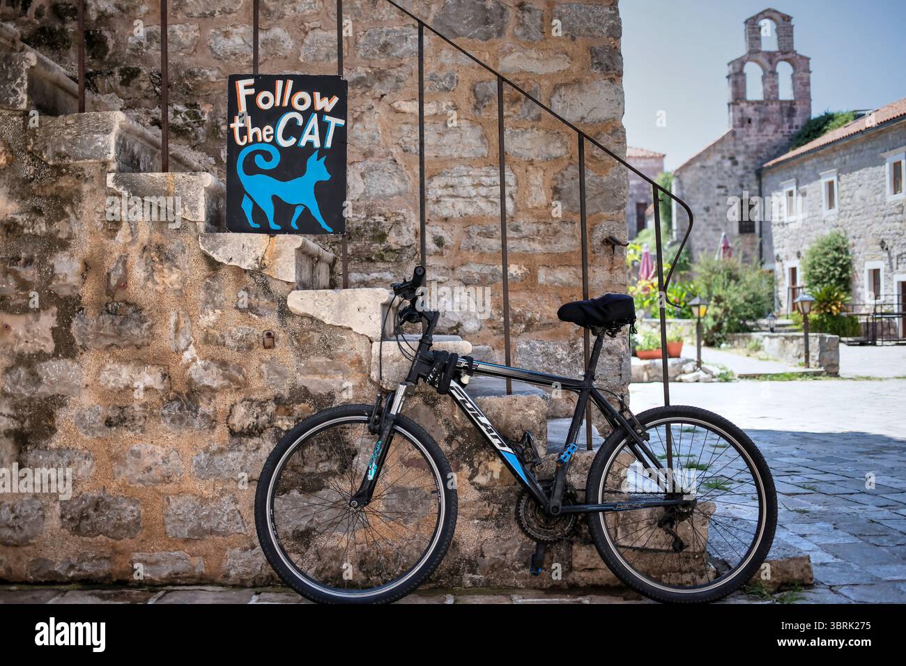Bicicletta parcheggiata da un cartello "Segui il gatto" nella città vecchia di Budva, Montenegro Foto Stock