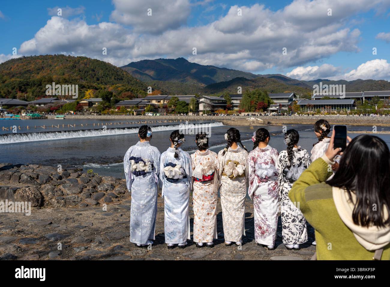 Un gruppo di giovani donne vestite con splendidi kimono tradizionali posano felicemente per una foto ricordo sul fiume Katsura ad Arashiyama. Kyoto, Giappone. Foto Stock