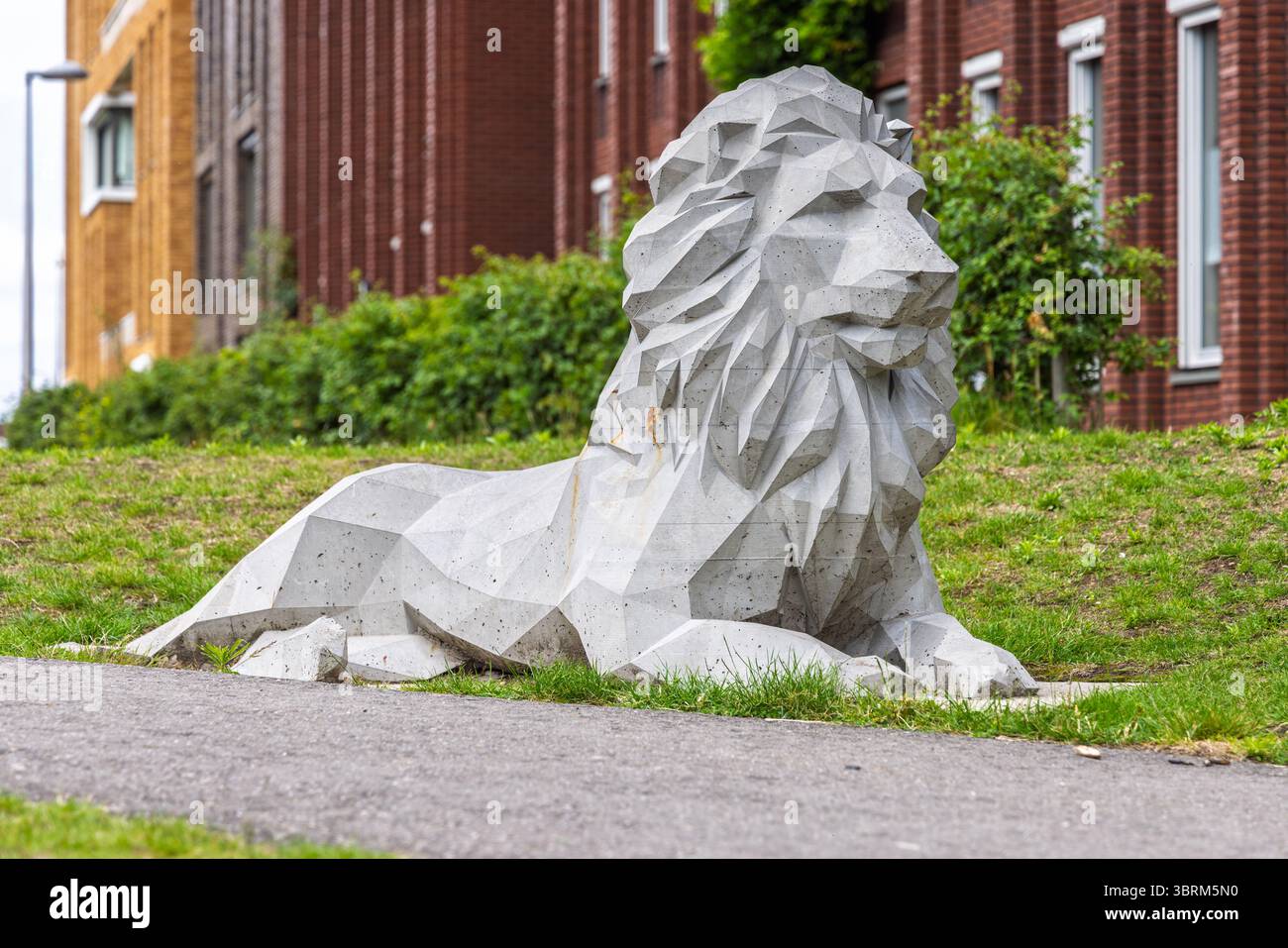 Moderna scultura geometrica di leoni in cemento, situata su un'area erbosa vicino a un marciapiede in un quartiere urbano con edifici in mattoni e legno. Foto Stock
