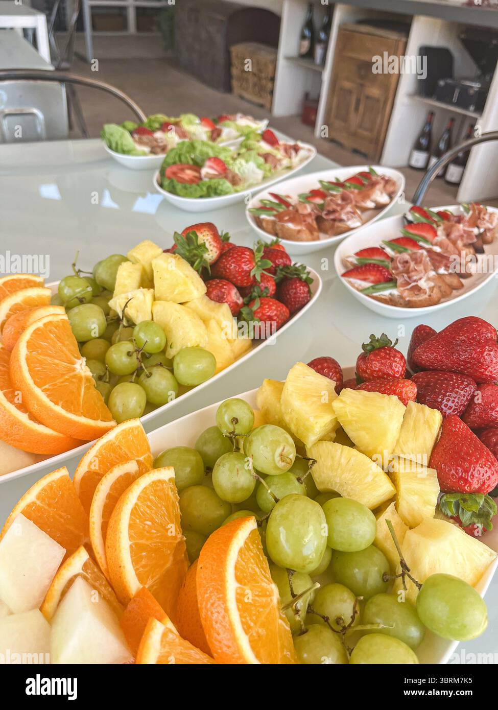 Vassoio di frutta fresca con arance, uva, fragole e ananas disposti splendidamente su un tavolo, favorendo un'alimentazione sana e vivaci pres Foto Stock