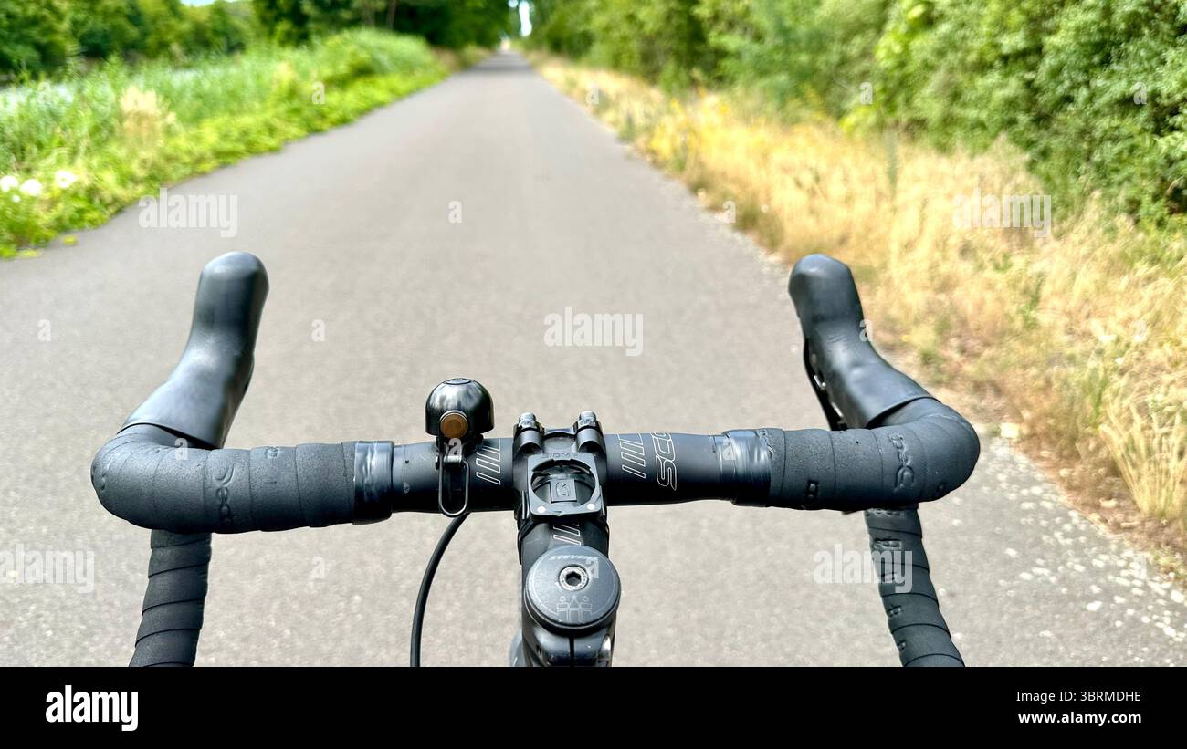 Una strada vista dalla prospettiva di un ciclista su una bicicletta senza mani sul bar Foto Stock
