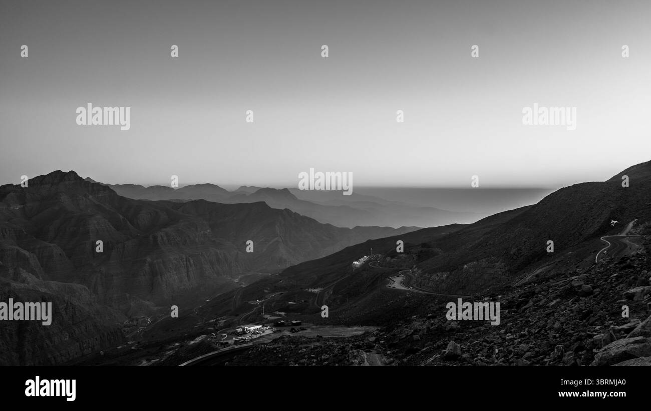 Vista cinematografica del tramonto sulle montagne con vista sul mare, silhouette, sfondo fotografico in bianco e nero Foto Stock