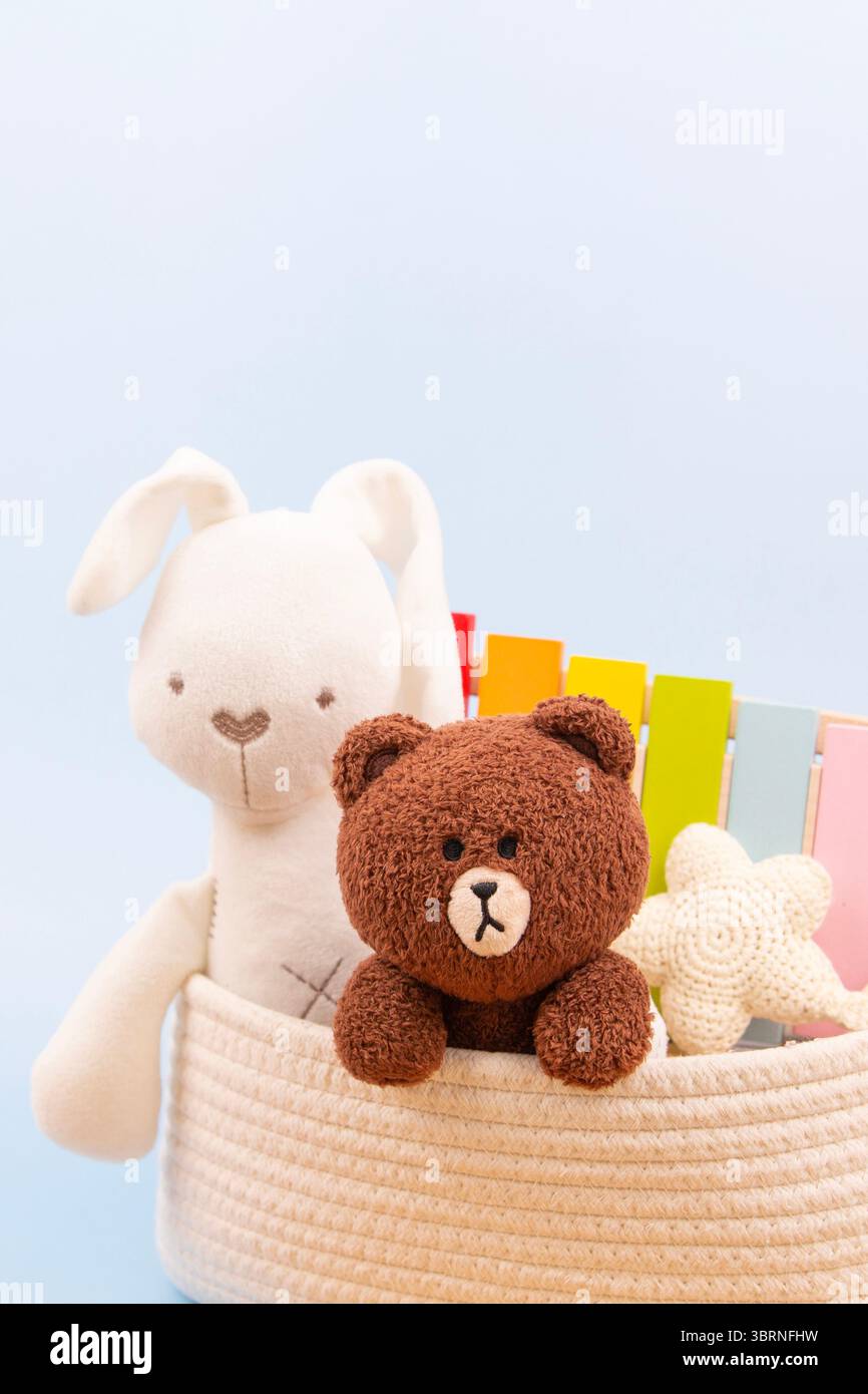 Sfondo astratto dei giocattoli per bambini. Morbidi giocattoli di peluche e giocattoli educativi in legno in una custodia bianca su sfondo azzurro. Vista frontale Foto Stock