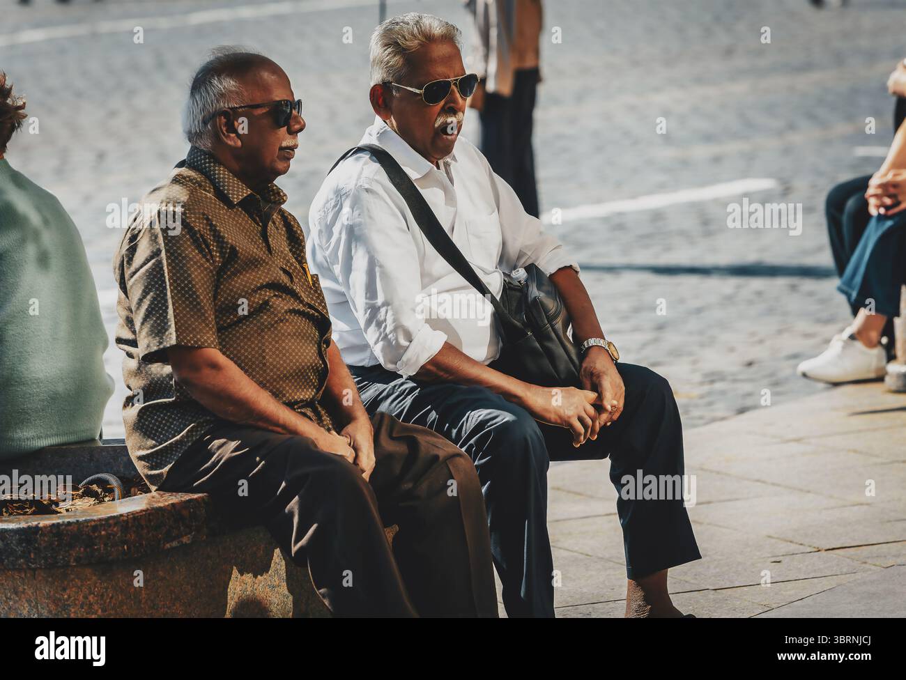 due persone anziane sono sedute per strada Foto Stock