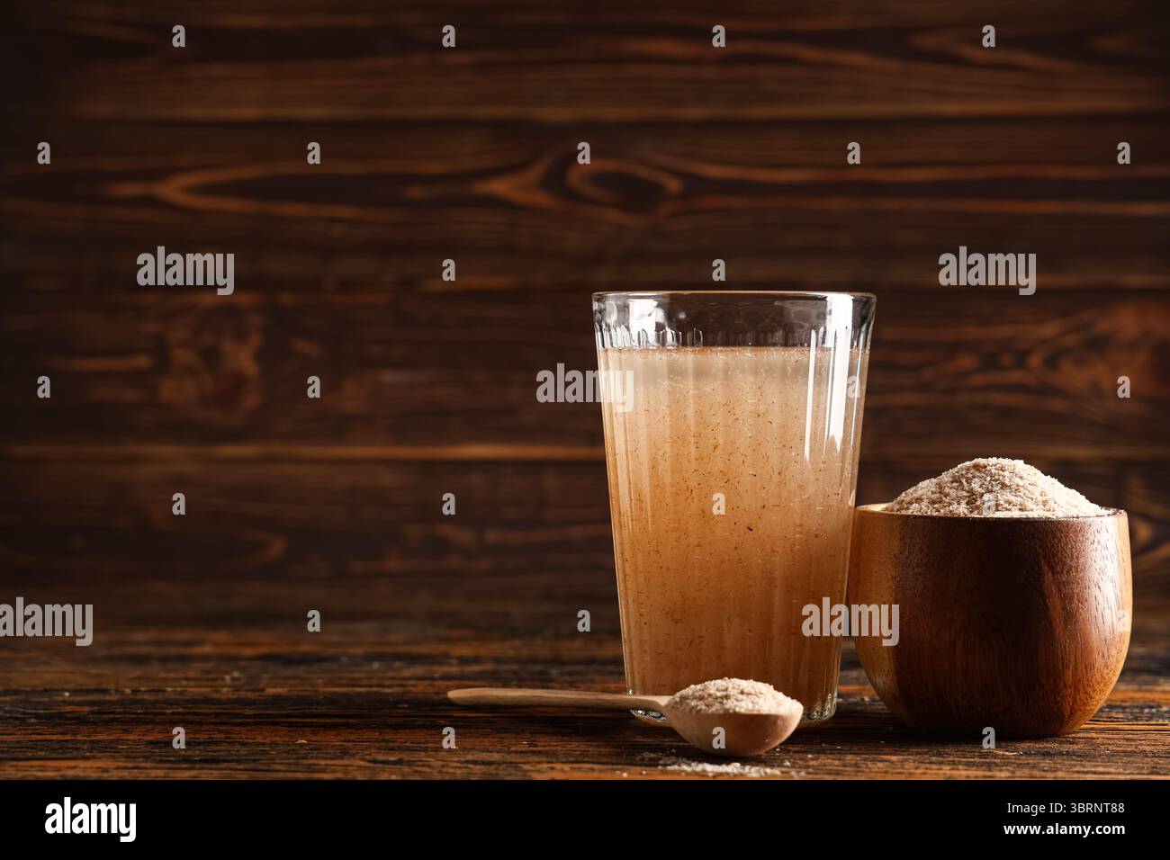 Bicchiere d'acqua con buccia di psico su fondo di legno Foto Stock